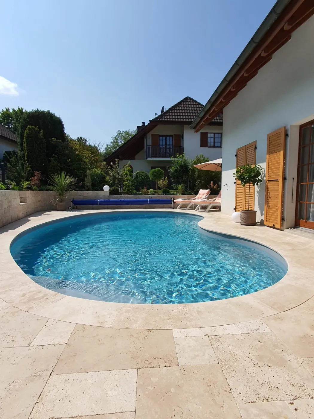 Piscine Waterair forme haricot, margelle en travertin — réalisation Magicpool